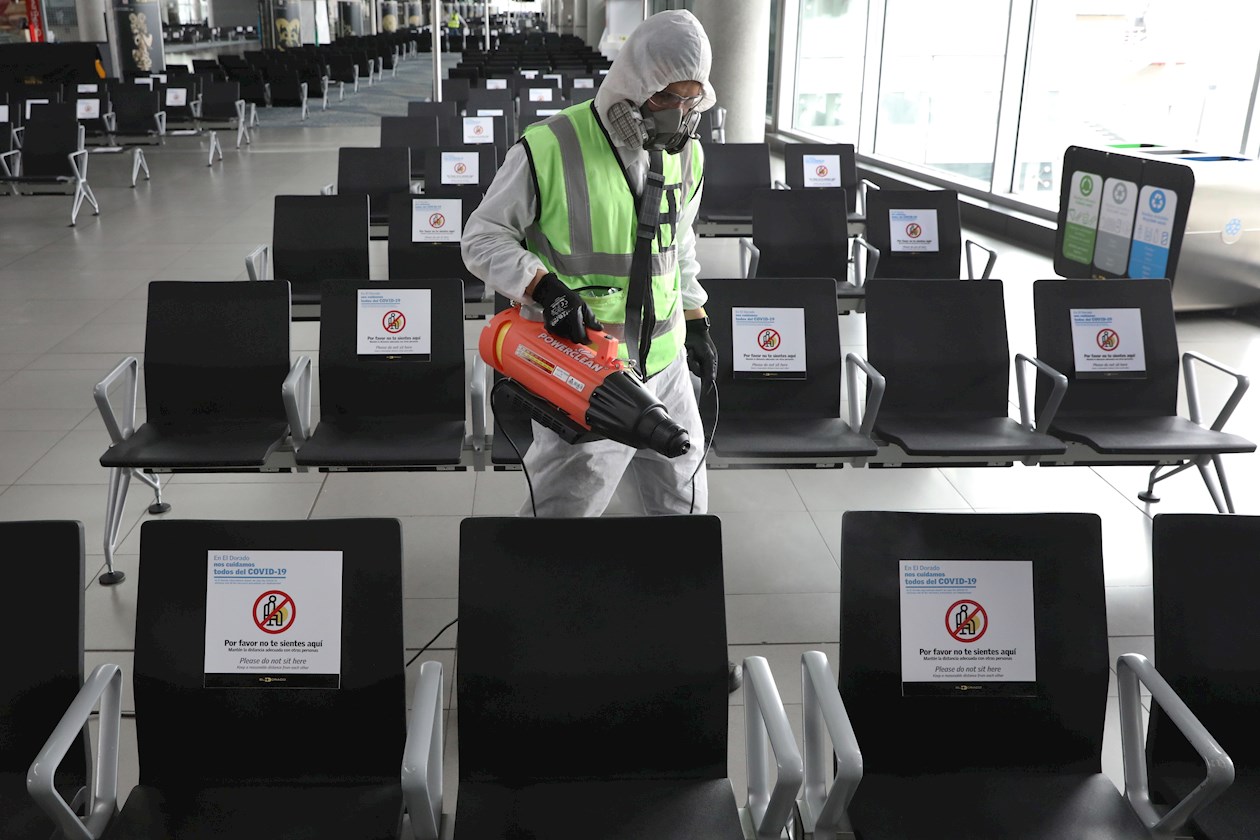 Un empleado desinfecta este jueves las sillas de una sala de espera en el Aeropuerto Internacional El Dorado, en Bogotá.