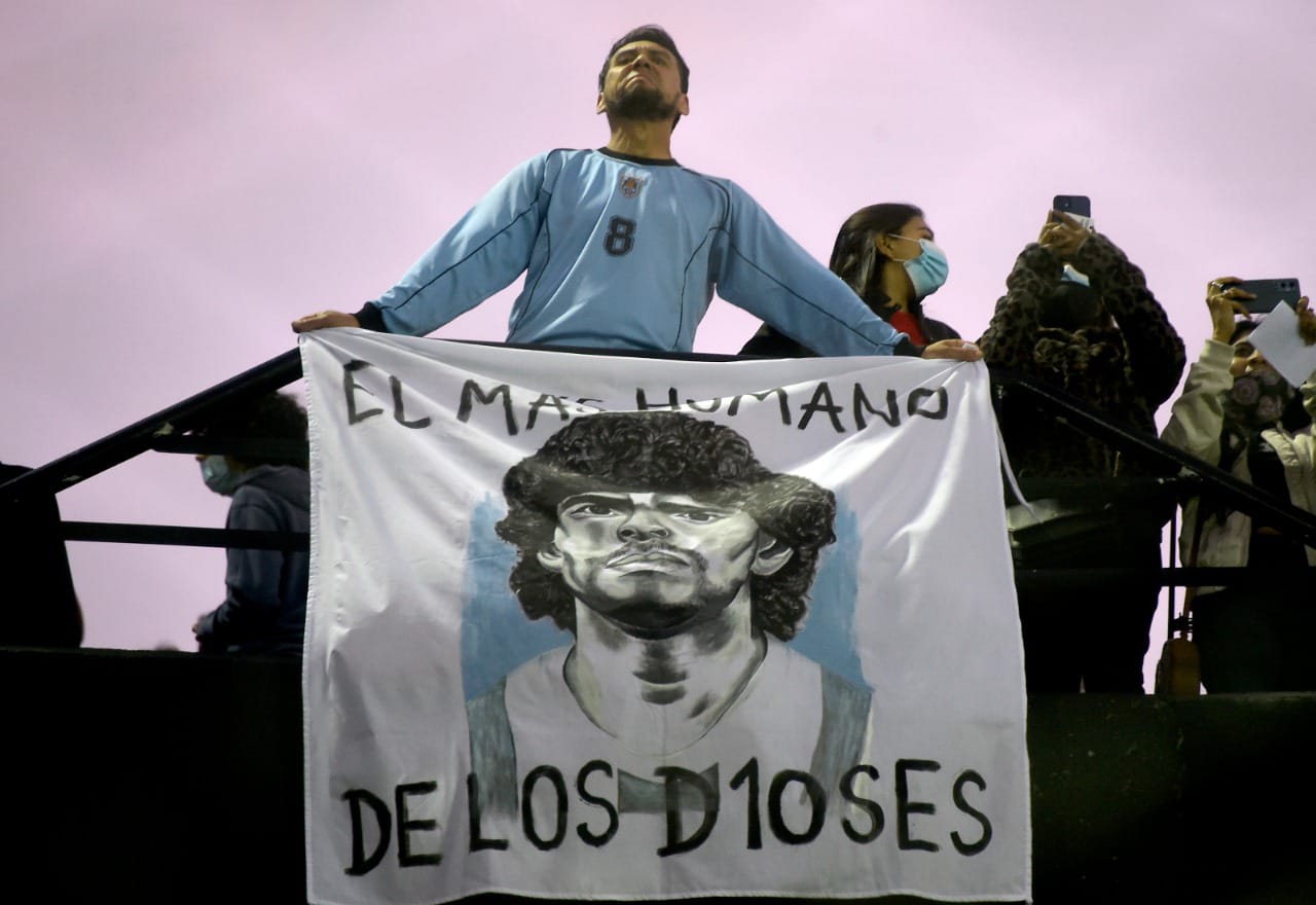 Un hincha sostiene una bandera dedicada a Maradona. 