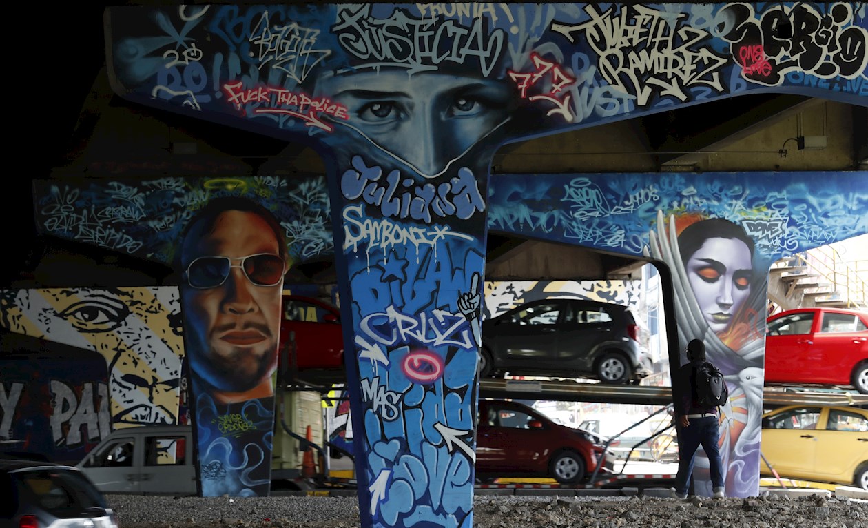 Los coches pasan sin detenerse por la Avenida Boyacá, mientras varios artistas callejeros, encaramados a tarimas, acaban casi medio centenar de retratos que rinden homenaje a líderes y lideresas sociales asesinados y víctimas de la violencia policial.