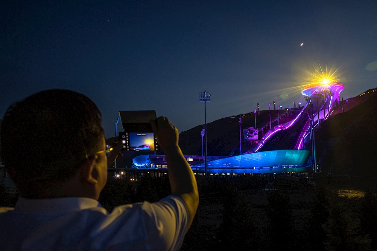 Un hombre toma fotos de un espectáculo de luces desde el Centro Nacional de Salto de Esquí, una de las sedes de los Juegos Olímpicos y Paralímpicos de Invierno de Beijing 2022.