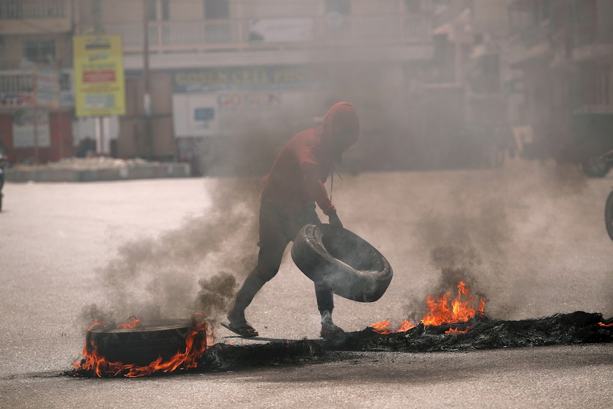 Un hombre levanta una barricada en llamas durante una jornada de protestas a la vez que se rindieron homenajes al asesinado presidente Jovenel Moise, hoy, en Cap-Haitien (Haití). 