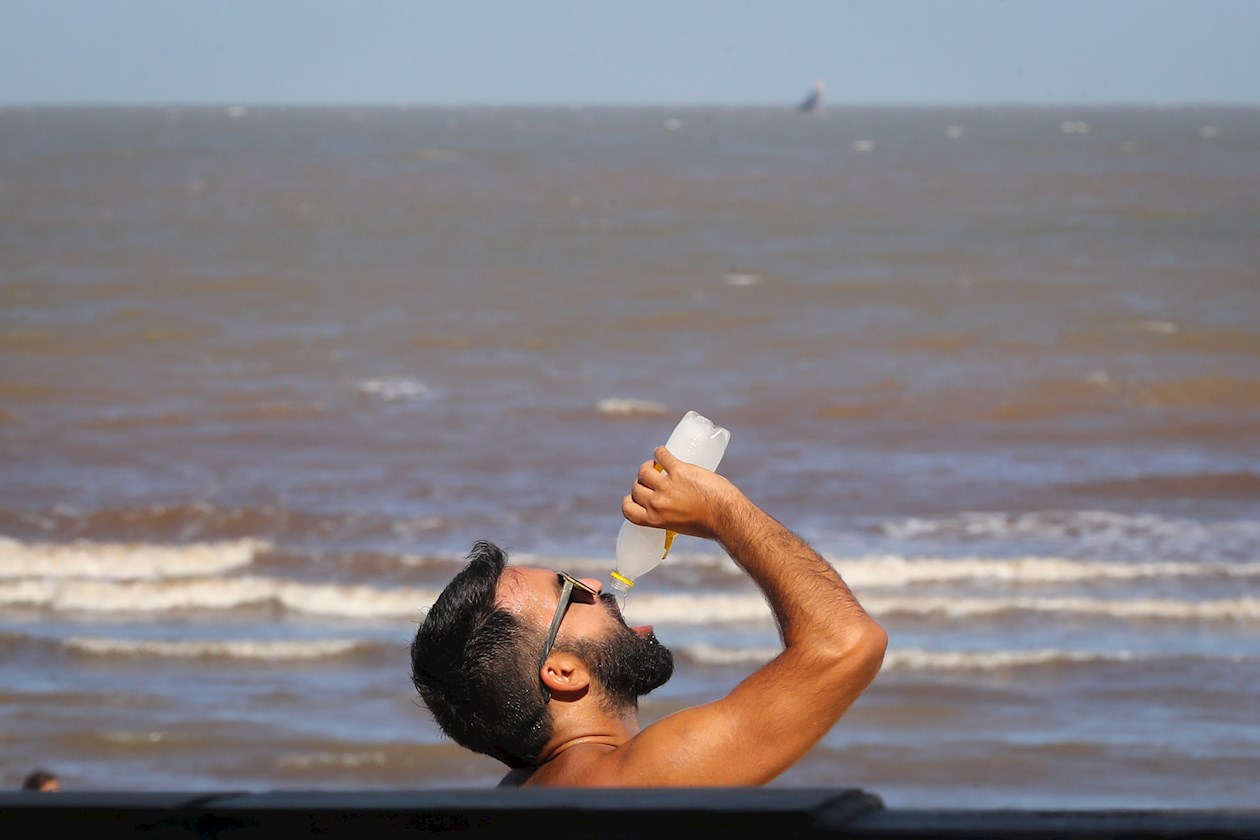 Un hombre bebe líquido en la Playa Pocitos de Montevideo este jueves, durante la ola de calor que rige desde el pasado martes y se extenderá hasta el próximo domingo.