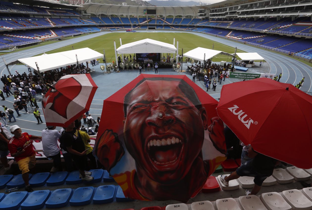 Un aficionado usa un paraguas con la imagen del exfutbolista colombiano Freddy Rincón.