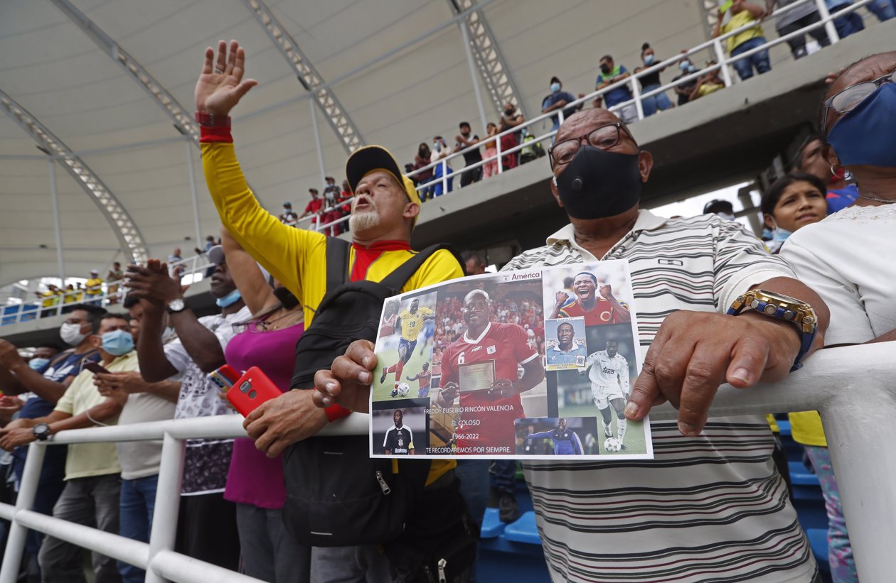 Un aficionado sostiene una fotografía con imágenes del exfutbolista colombiano Freddy Rincón.