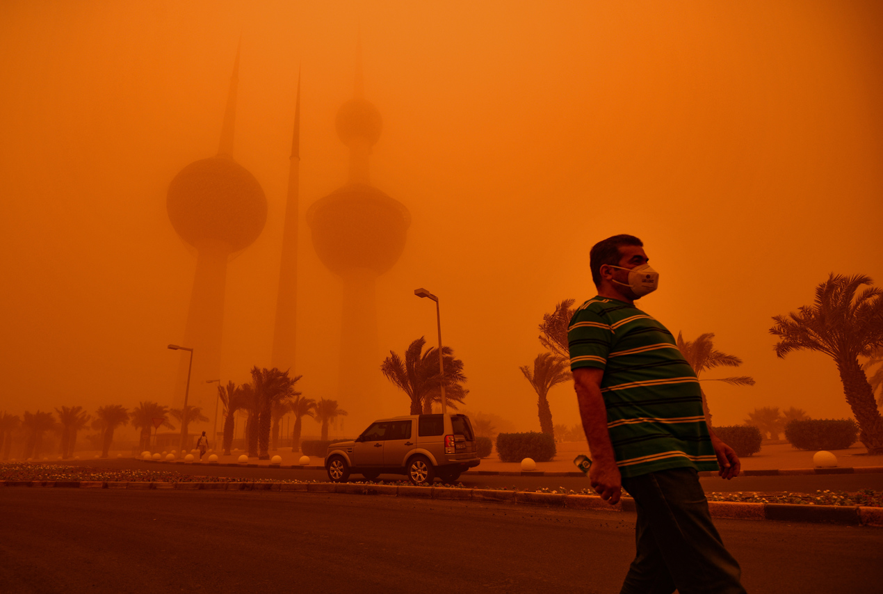 Un hombre pasa frente a las Torres de Kuwait envueltas en polvo en la ciudad de Kuwait.