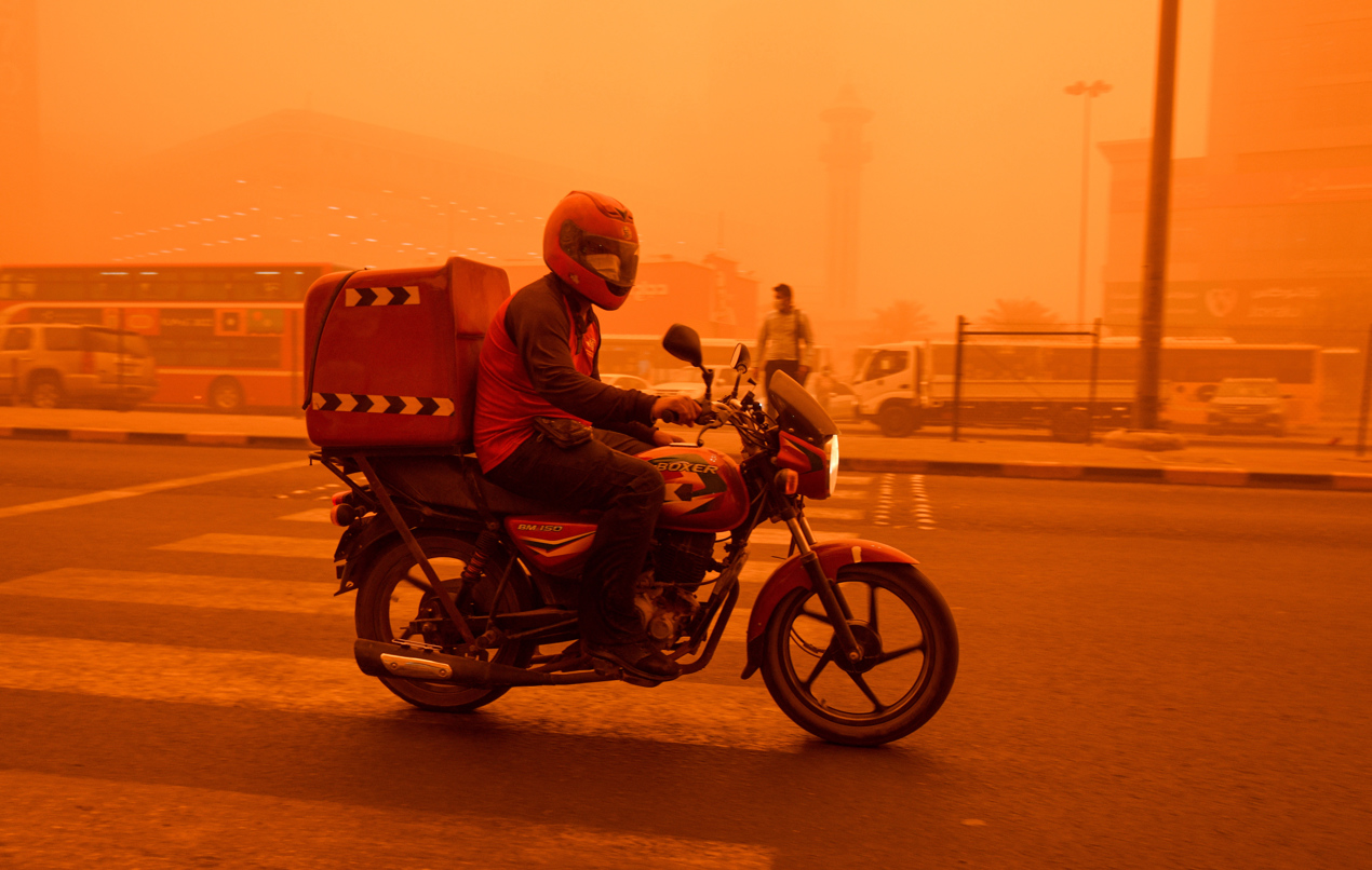  Un hombre monta en moto durante una fuerte tormenta de polvo en la ciudad de Kuwait.