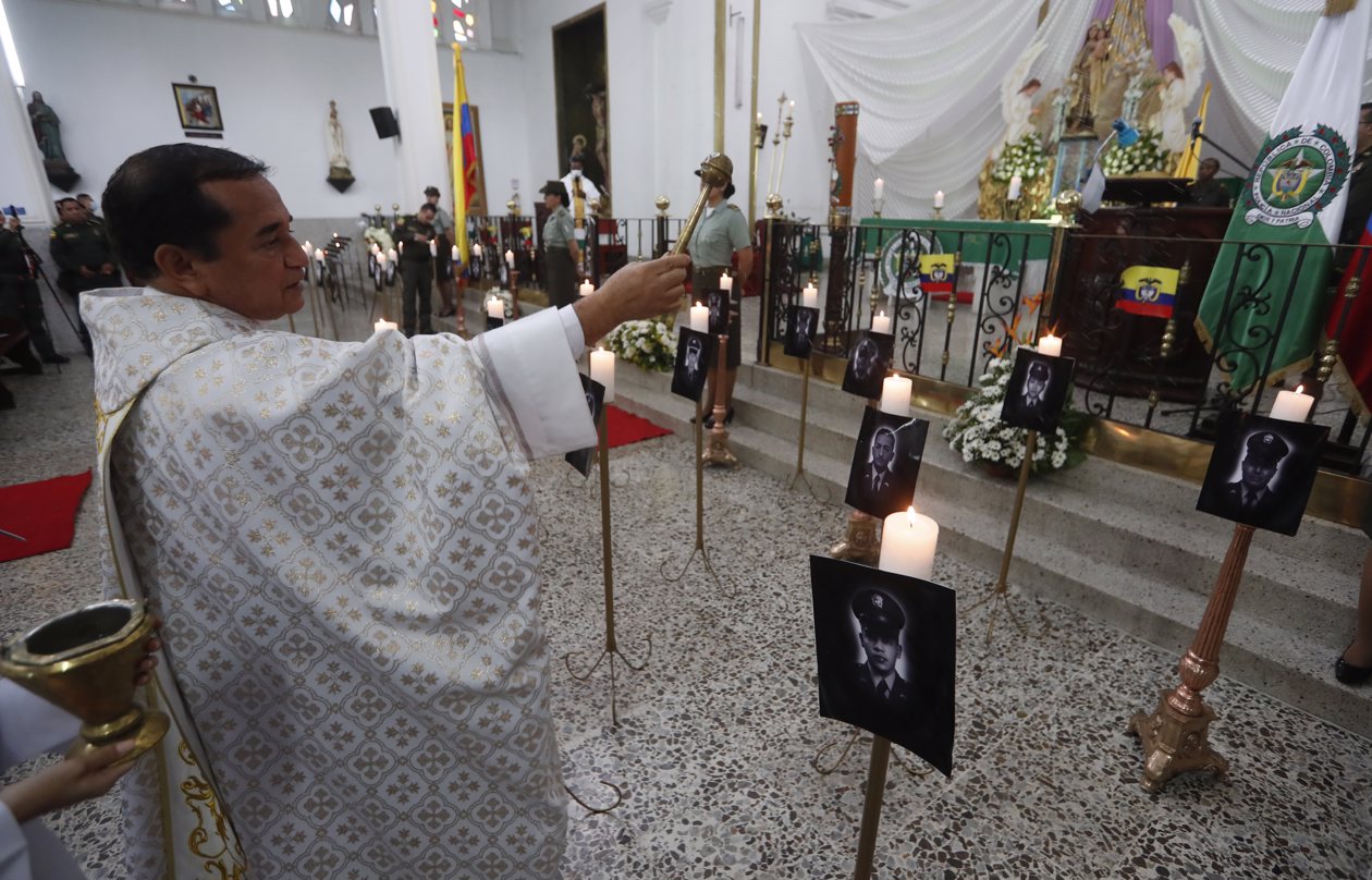 Un sacerdote oficia eremonia religiosa en honor a los policías asesinados recientemente en el país por el 'Clan del Golfo', en Cali.