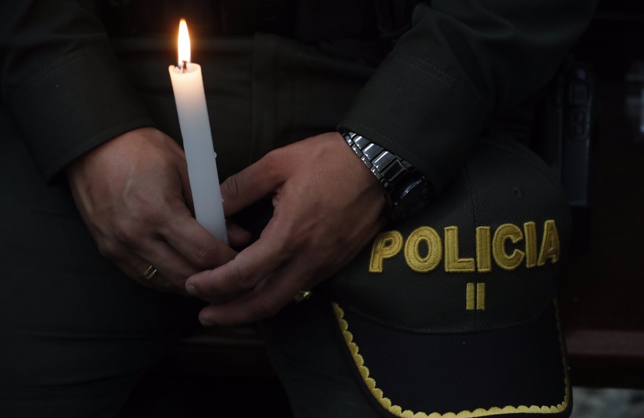 Un policía sostiene una vela en honor a sus compañeros asesinados recientemente en el país por el 'Clan del Golfo', en Cali.