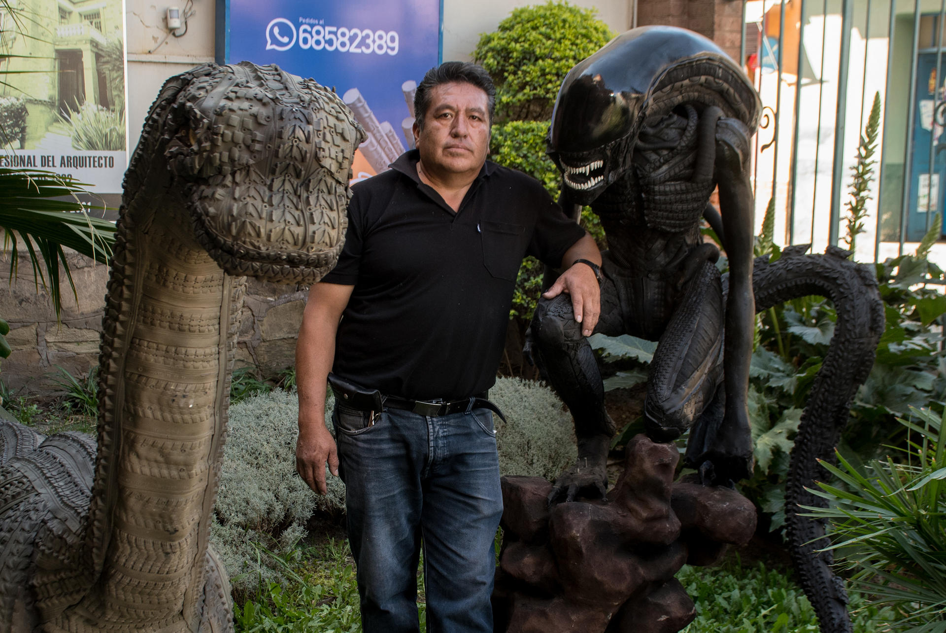 Sandro Arellano posa junto a dos de sus eculturas.