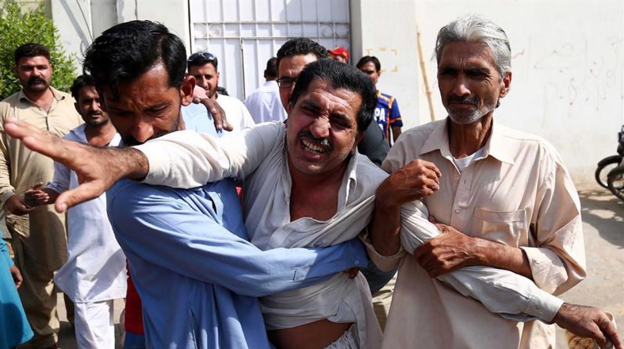 Dos hombres consuelan al familiar de una víctima tras el ataque perpetrado contra el consulado de China en Karachi, Pakistán.