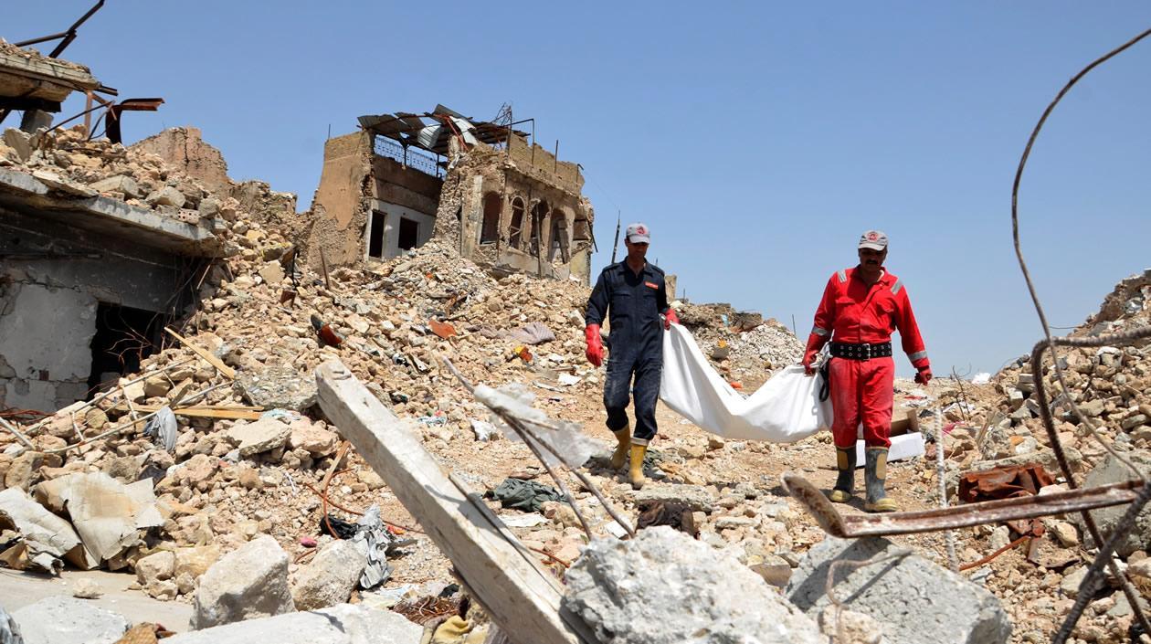 Miembros de los servicios transportan los cuerpos de varias personas encontradas bajo los escombros de un edificio en Mosul, Irak