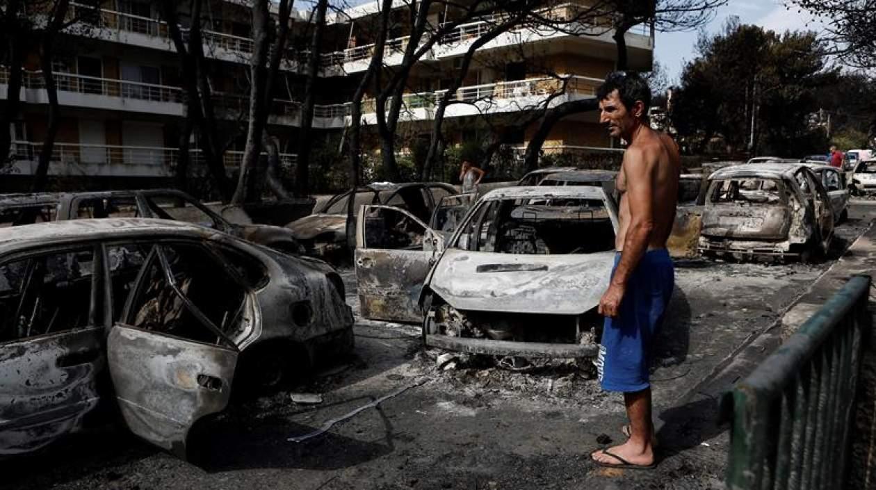 Un residente observa el estado en que han quedado varios coches calcinados tras el paso de las llamas por Mati, barrio del noreste de Atenas (Grecia) .