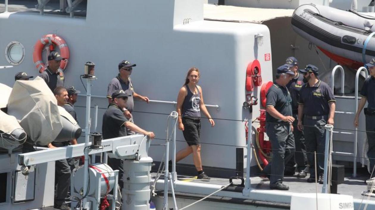 Carola Rackete (c), capitana del buque de rescate Sea Watch 3, es escoltada por efectivos de la Guardia di Finanza italiana a su llegada a Porto Empedocle (Italia) este lunes. 