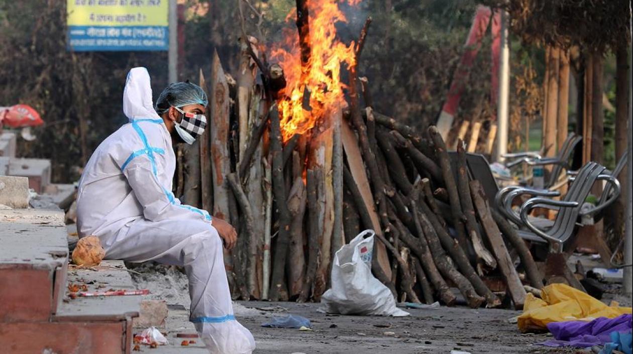 Un hombre ataviado con un traje aislante descansa tras realizar rituales funerarios a sus familiares difuntos en Nueva Delhi. 