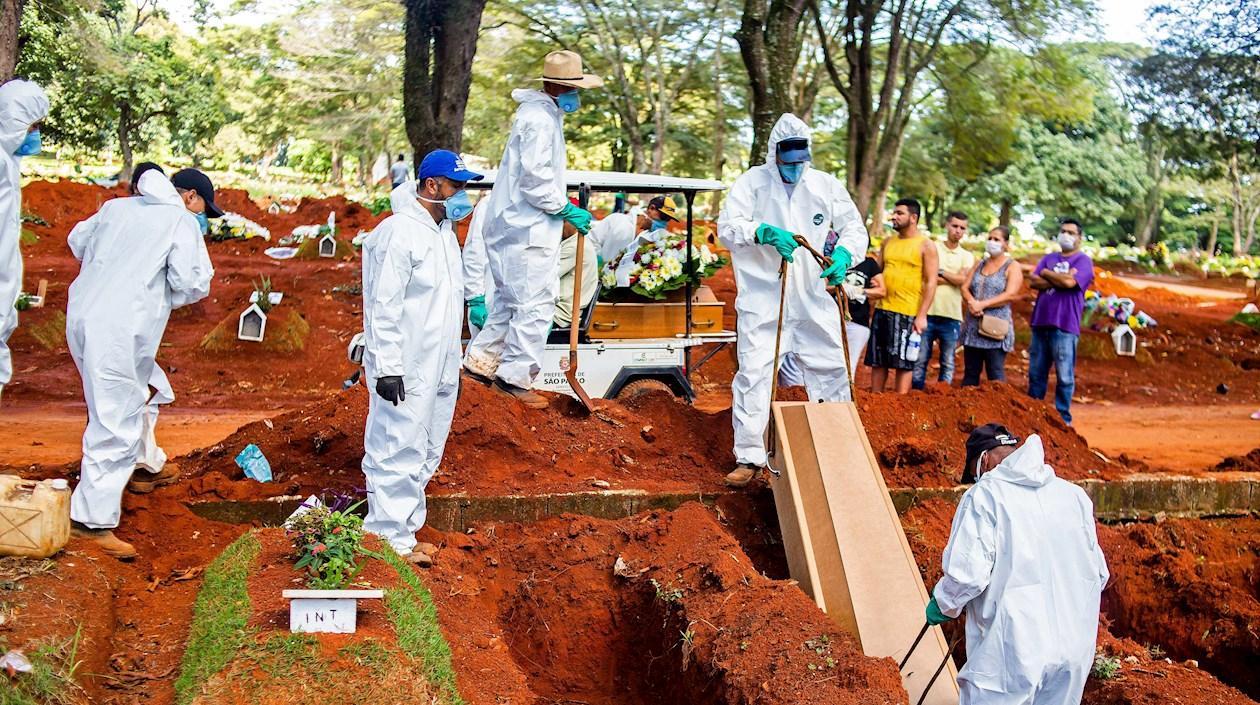 Empleados del servicio funerario entierran a una víctima de la covid-19, en el cementerio de Vila Formosa, en São Paulo (Brasil).
