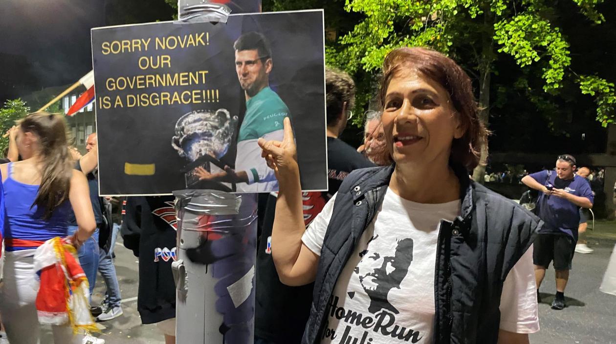Mujer sostiene cartel en apoyo a Novak Djokovic. 