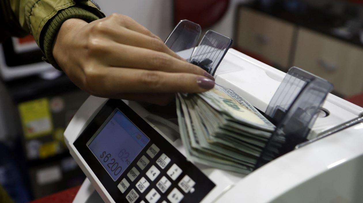 Una mujer coloca dólares en una máquina contadora de billetes en una casa de cambio de divisas, en Bogotá.