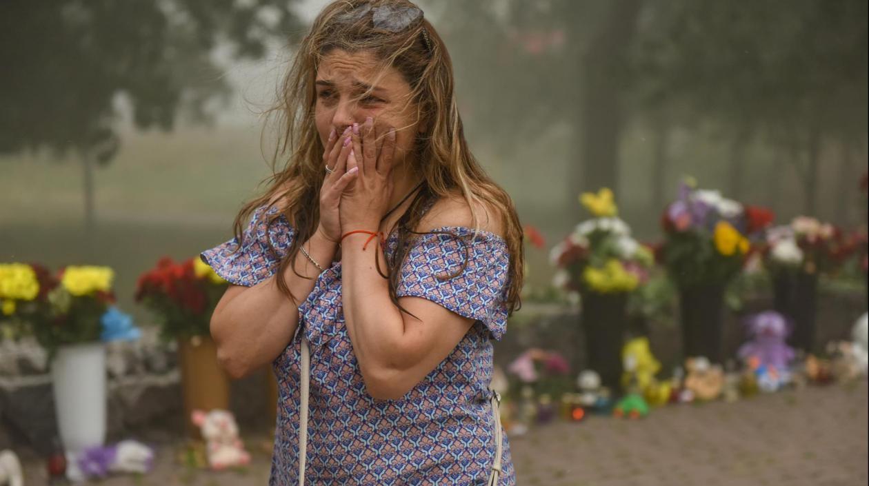 Una mujer llora teniendo de fondo las flores que llevaron al centro comercial de Kremenchuk tras el ataque con misiles.