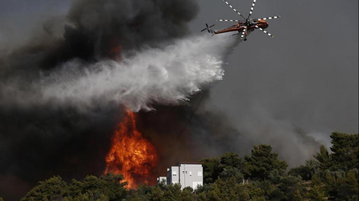 Un helicóptero trata de controlar el fuego en Atenas, la zona más golpeada.