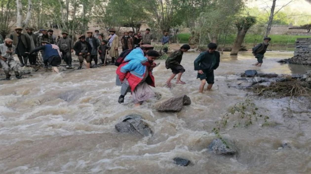 Varias personas atraviesan aguas desbordadas en Afganistán.
