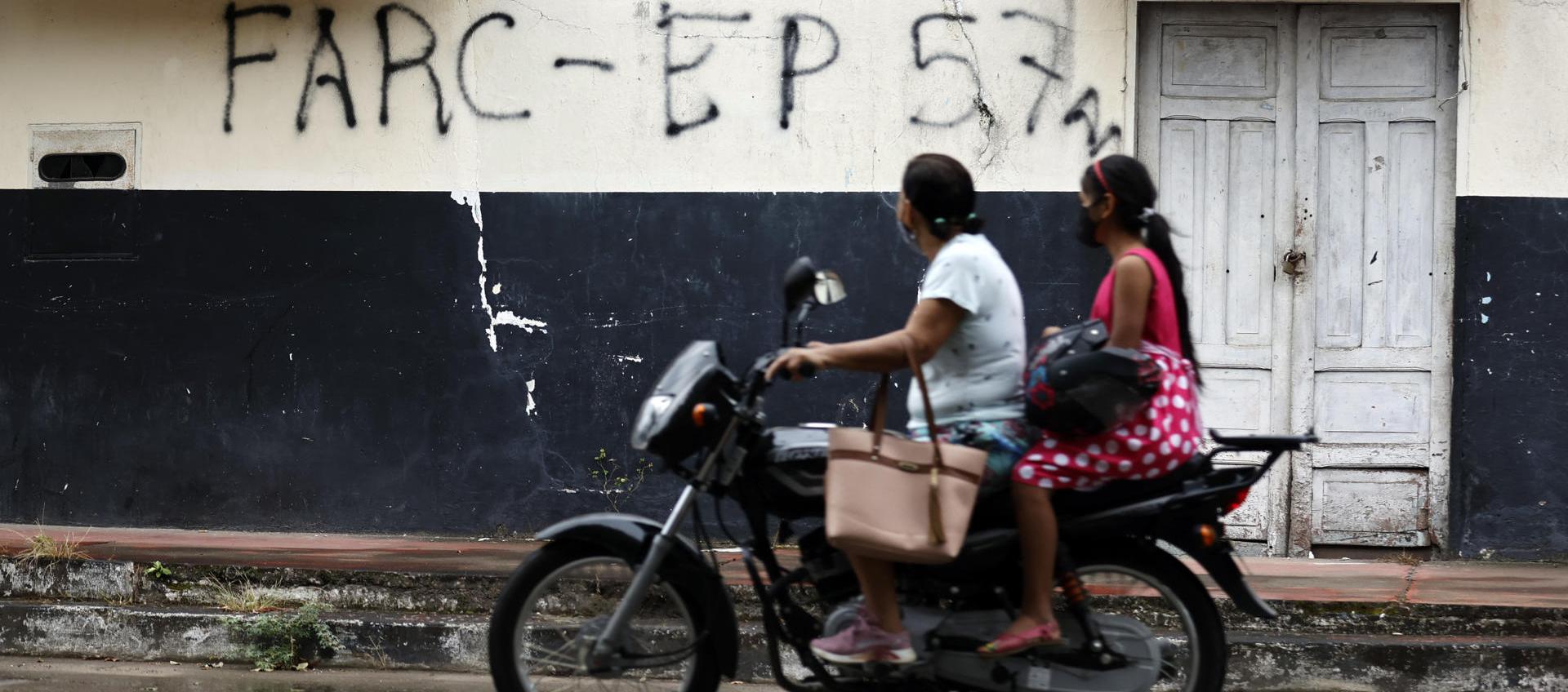 La imagen de archivo muestra a dos ciudadanos de Saravena (Arauca) pasando frente a una pared rayada con grafitis de FARC y EP.