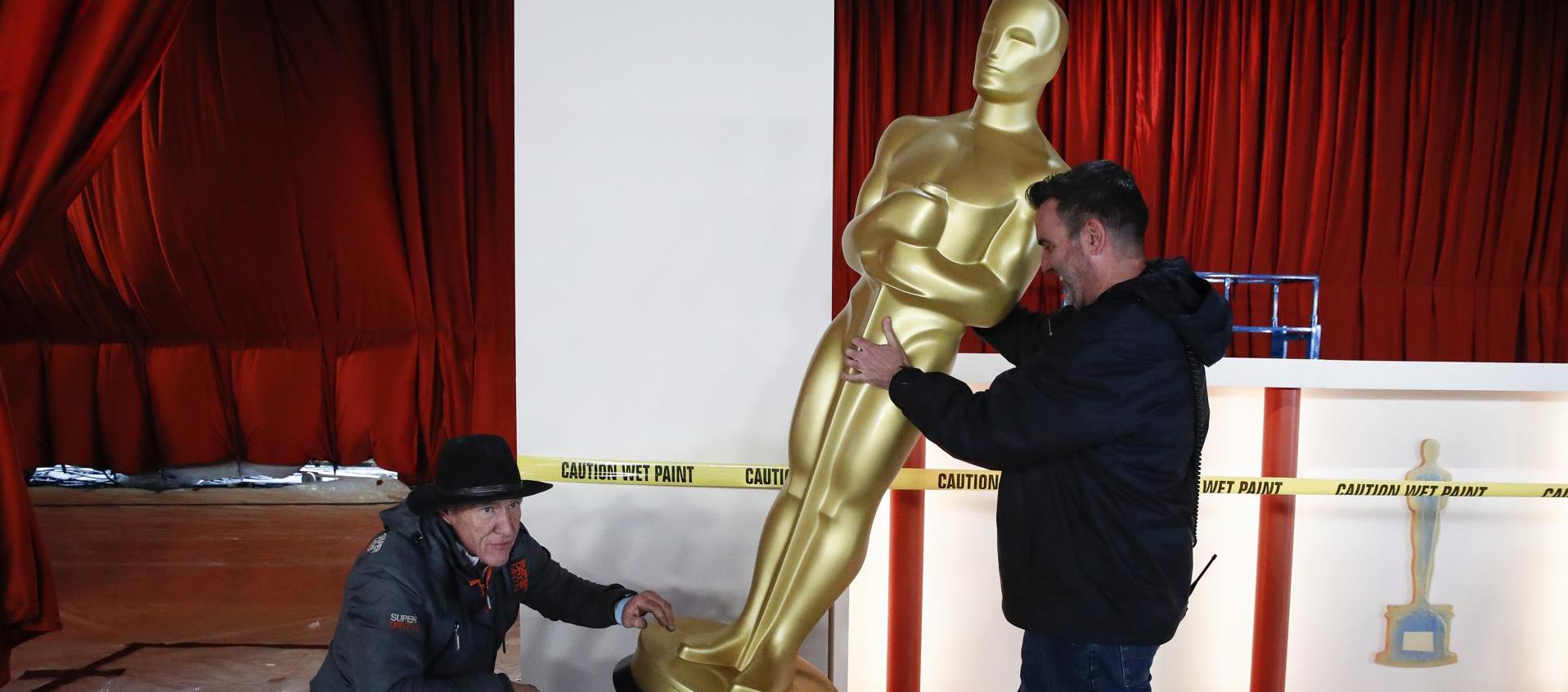 Dos hombres encargados de la logística mueven la figura icónica de los Premios Óscar 2023.