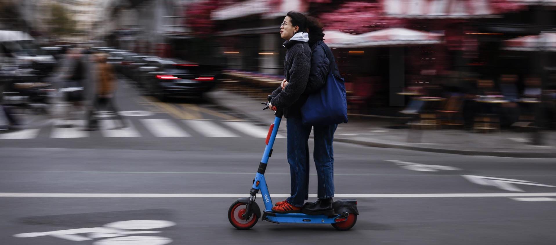 Dos usuarios se movilizan en una patineta eléctrica por las calles de París