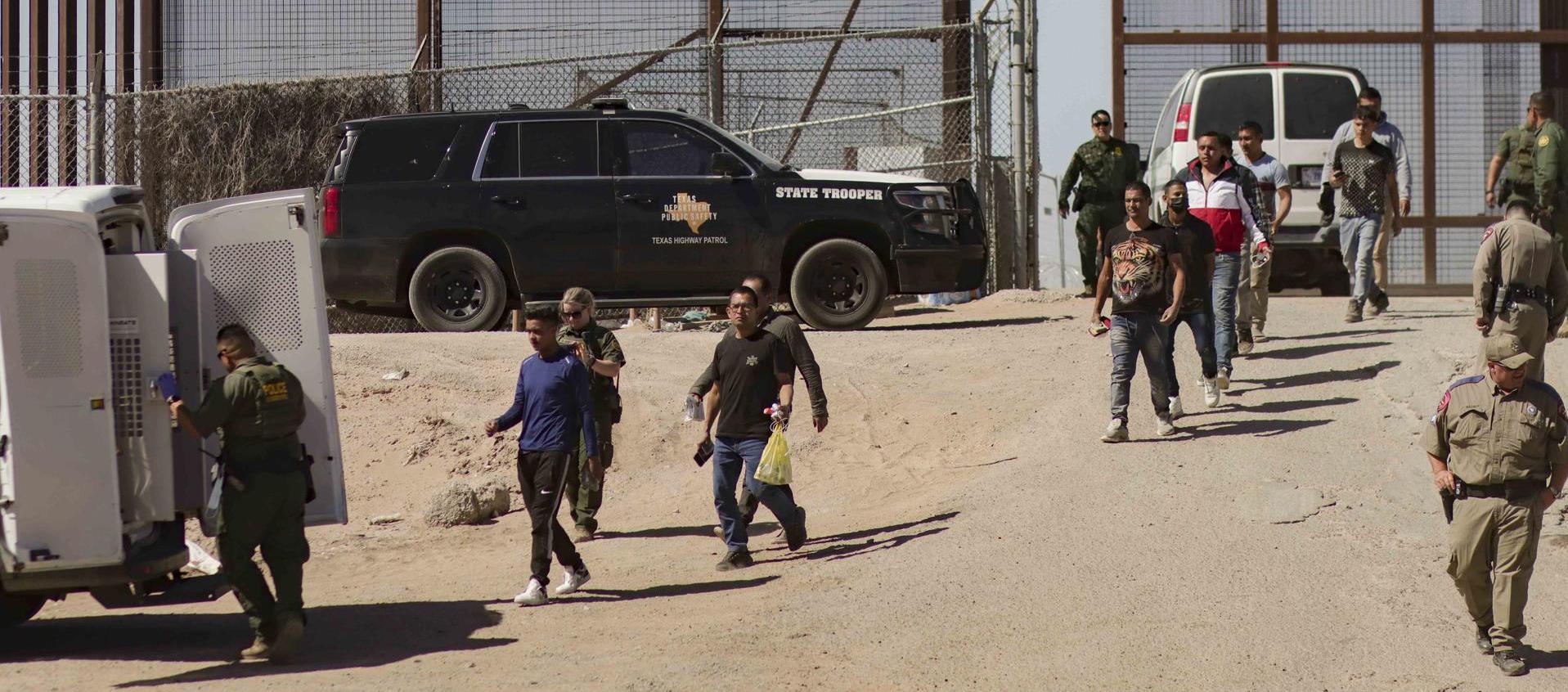 Migrantes detenidos son llevados este jueves por miembros de la Patrulla Fronteriza estadounidense a un vehículo, junto al muro fronterizo en El Paso, Texas 