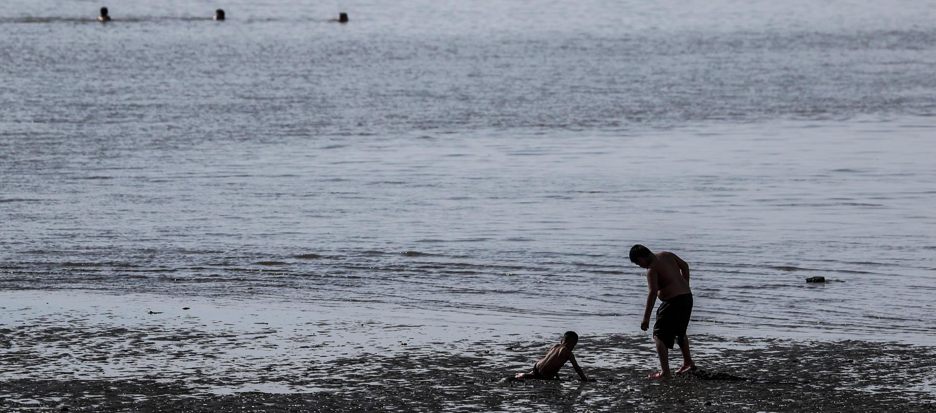 Un hombre y un niño se bañan en el Río de la Plata, en una fotografía de archivo