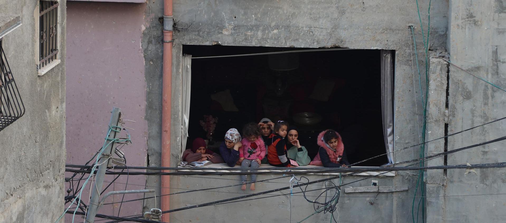 Mujeres y niñas palestinas observan la destrucción provocada por los bombardeos israelíes en el campo de refugiados de Nur Shams