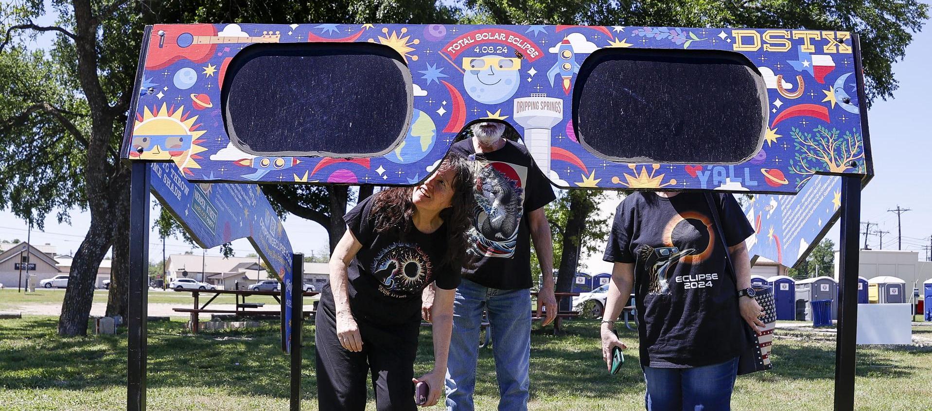 Una familia mira a través de un par de gafas gigantes especiales para el eclipse solar en el Veterans Memorial Park en Dripping Springs, Texas