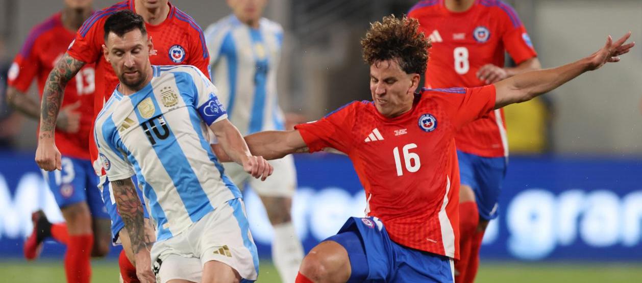 Lionel Messi disputa el balón con el chileno Igor Lichnovsky.