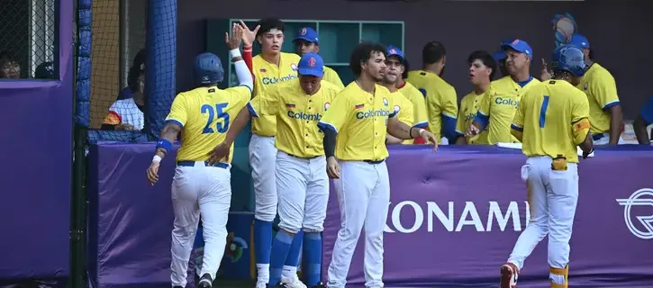 Peloteros de Colombia celebran una carrera en el dugout.