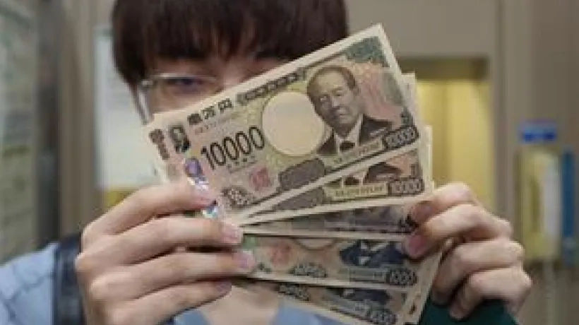 La primera persona que retira los billetes japoneses de nuevo diseño los enseña en Saitama, Japón.