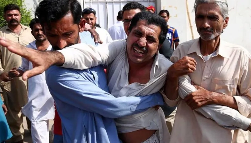 Dos hombres consuelan al familiar de una víctima tras el ataque perpetrado contra el consulado de China en Karachi, Pakistán.