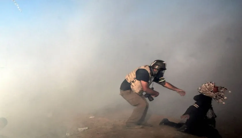 Un fotoperiodista trata de ayudar a una manifestante después de que los israelíes lanzaran gases lacrimógenos durante enfrentamientos registrados el pasado martes 15 de mayo, en la frontera con Israel, al este de la Franja de Gaza (Gaza). EFE