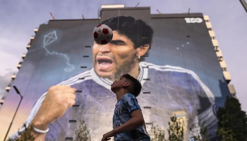 Niño juega con el balón, frente al mural de Diego Maradona. 