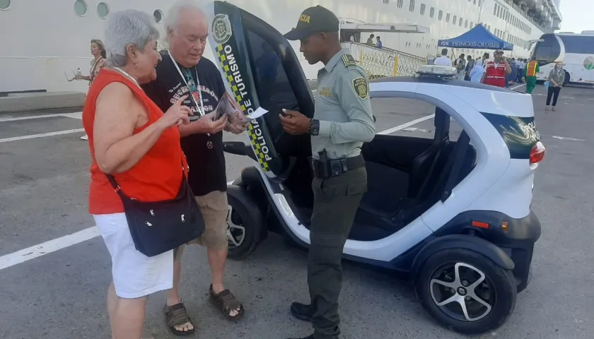 Un policía atiende a dos turistas que arribaron en un crucero a Cartagena.