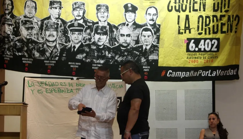  El coronel (r) Jaime Humberto Pinzón entrega una medalla otorgada por sus actuaciones militares hace 18 años a José Alexander Castro, del colectivo Tejiendo Memorias.