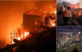 Varias personas intentan sofocar las llamas en sus viviendas que se han visto afectadas por un incendio forestal que alcanzó ayer en Valparaíso.
