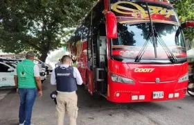Funcionario de Migración Colombia inspeccionan un bus. 