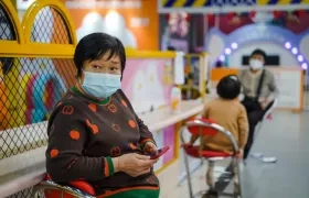 Una mujer protegida con una mascarilla utiliza su móvil en un centro comercial de Pekín.