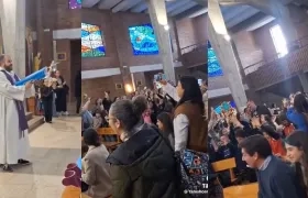 Párroco bendice a los niños de la iglesia con una pistola de agua.