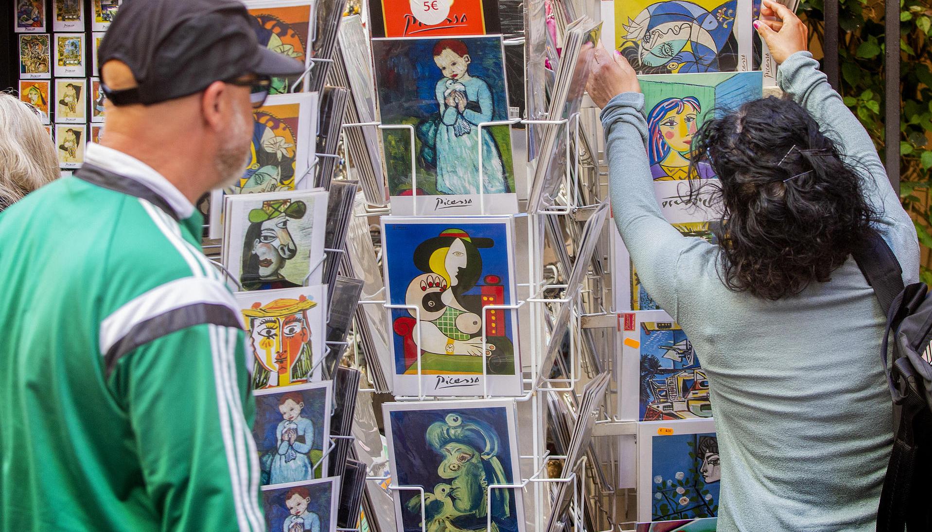  Turistas miran postales del artista español Pablo Ruiz Picasso.
