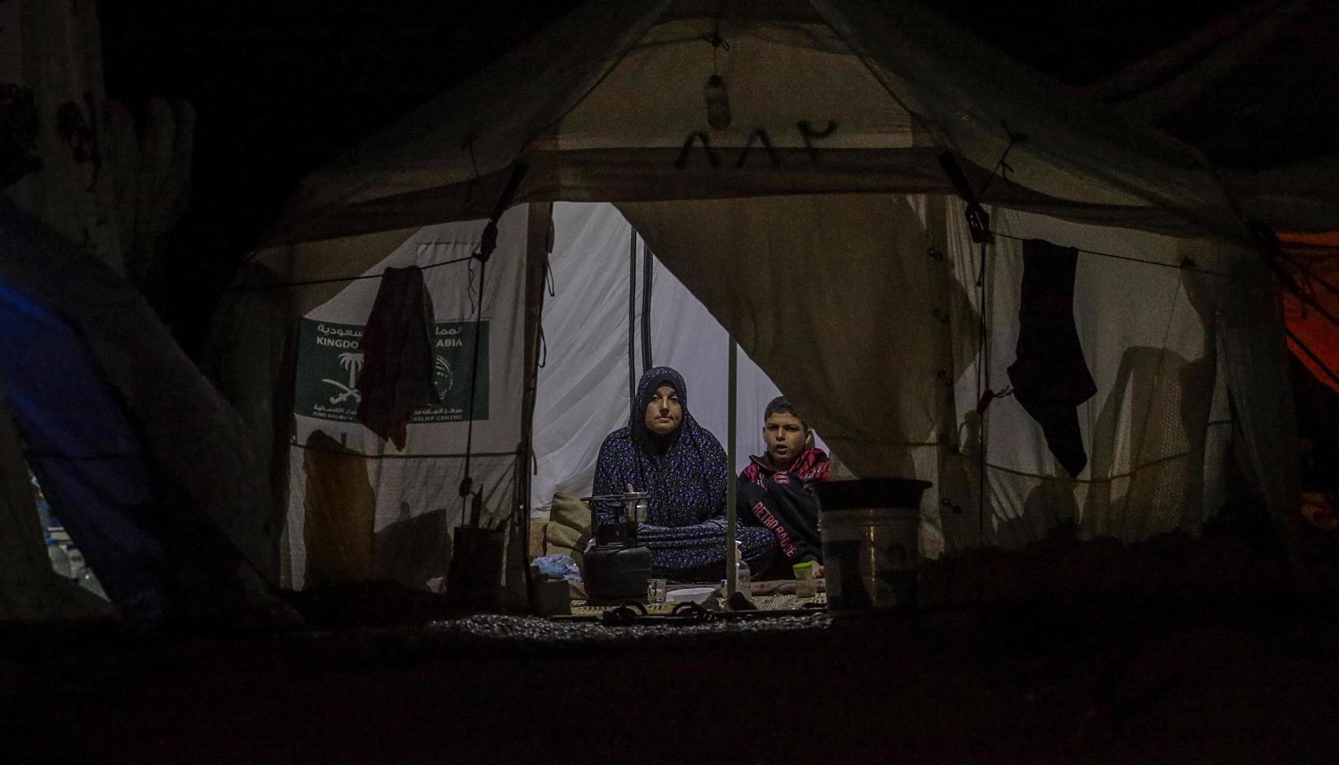 Una mujer palestina y su hijo que huyeron con su familia del norte de la Franja de Gaza se sientan dentro de su refugio en Deir al Balah, sur de la Franja de Gaza