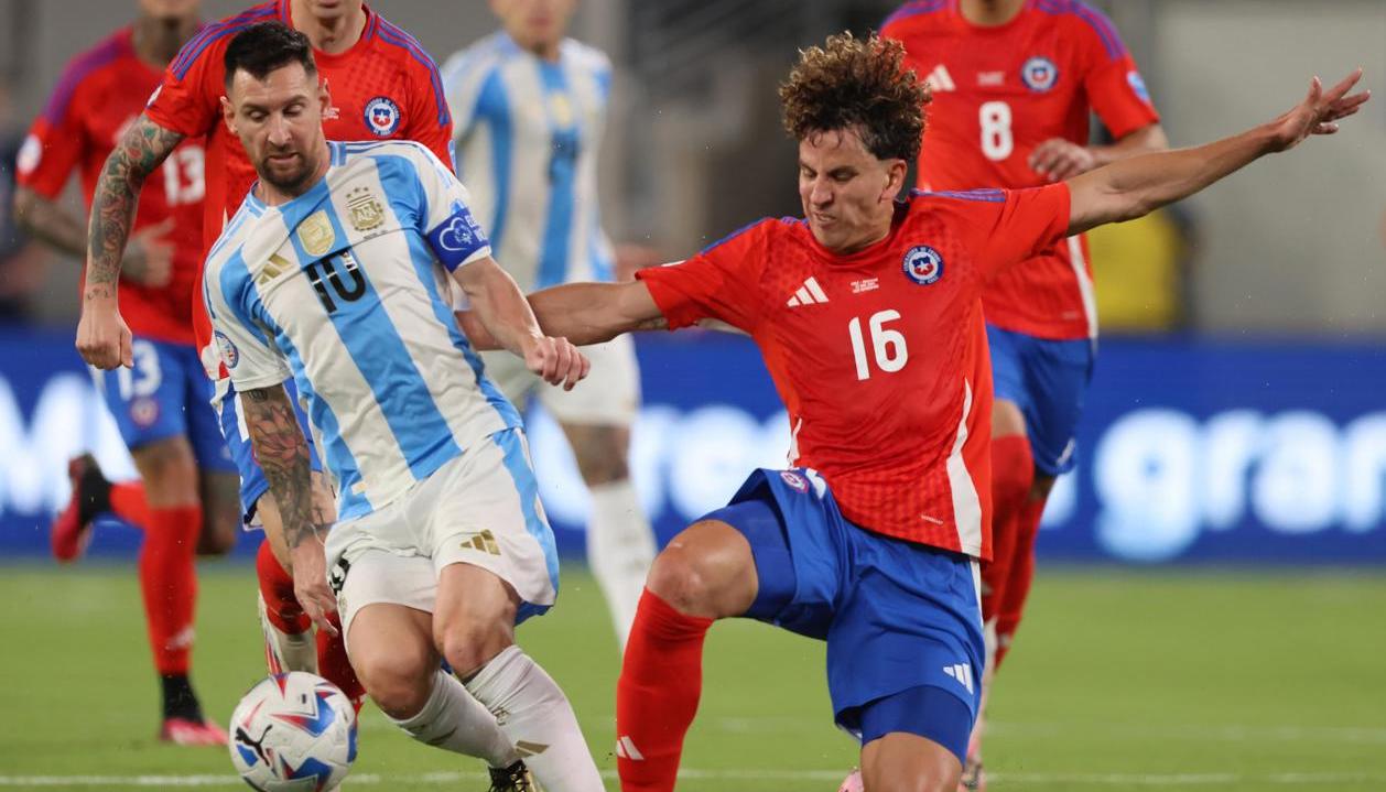 Lionel Messi disputa el balón con el chileno Igor Lichnovsky.