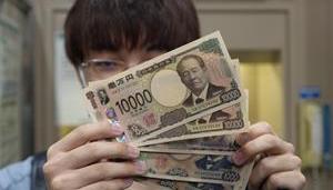 La primera persona que retira los billetes japoneses de nuevo diseño los enseña en Saitama, Japón.