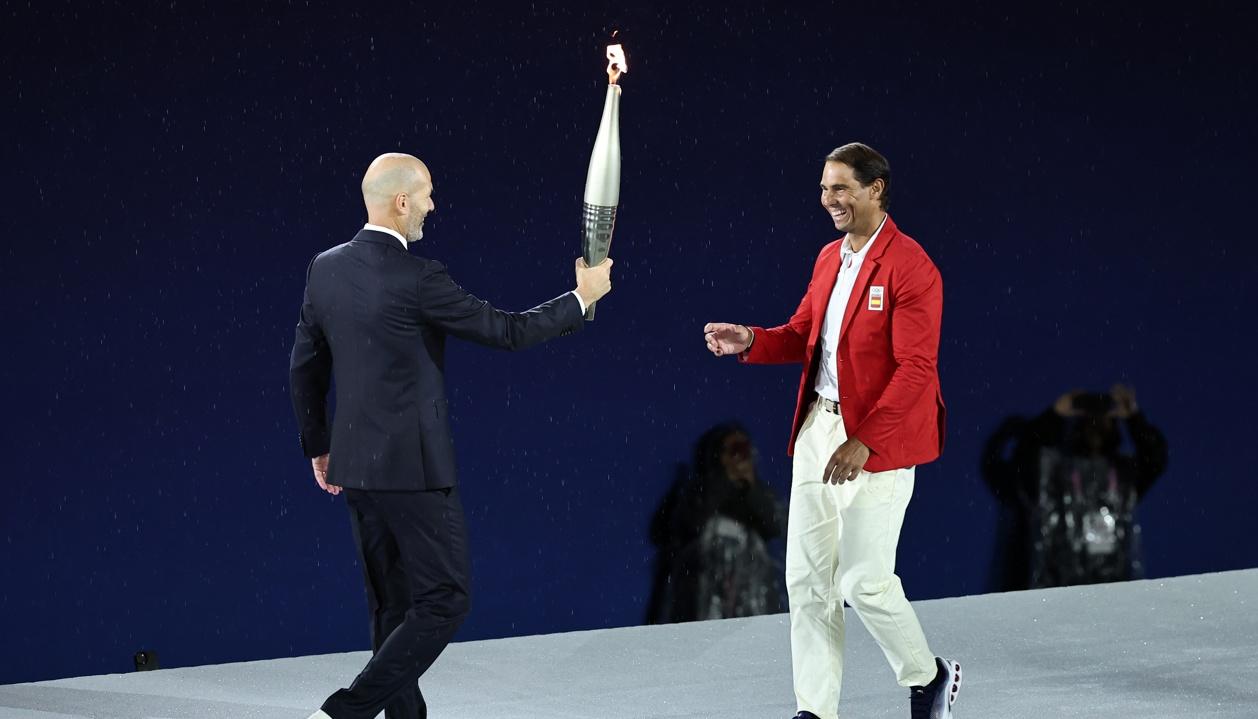 Zinedine Zidane entrega la antorcha olímpica al tenista español Rafael Nadal. 