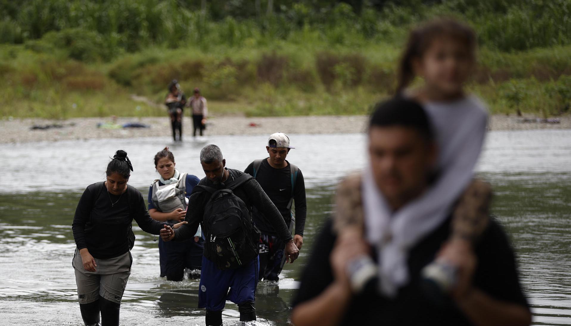 Migrantes cruzando el río Tuquesa luego de atravesar la selva del Darién, en Panamá.