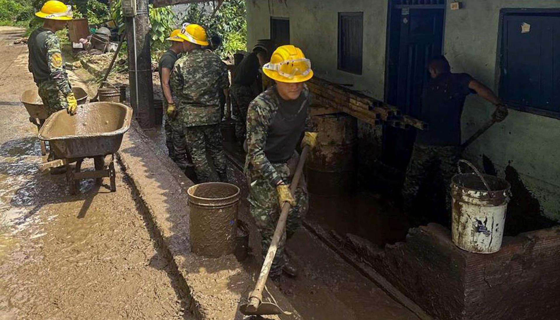 Soldados ayudan a remover escombros por un deslizamiento de tierra.